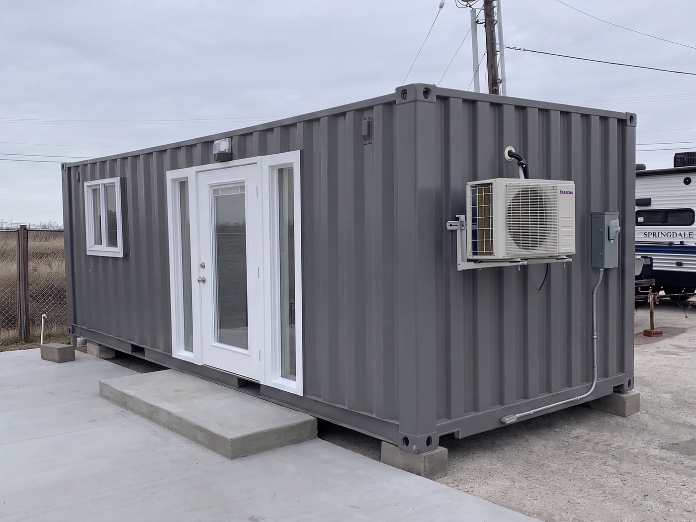 A charcoal 20-foot cabin with a white full-light door and a mini split condenser on the wall